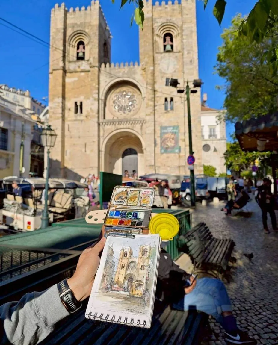 Painting Lisbon cathedral from a bench, the finished watercolour held up against it
